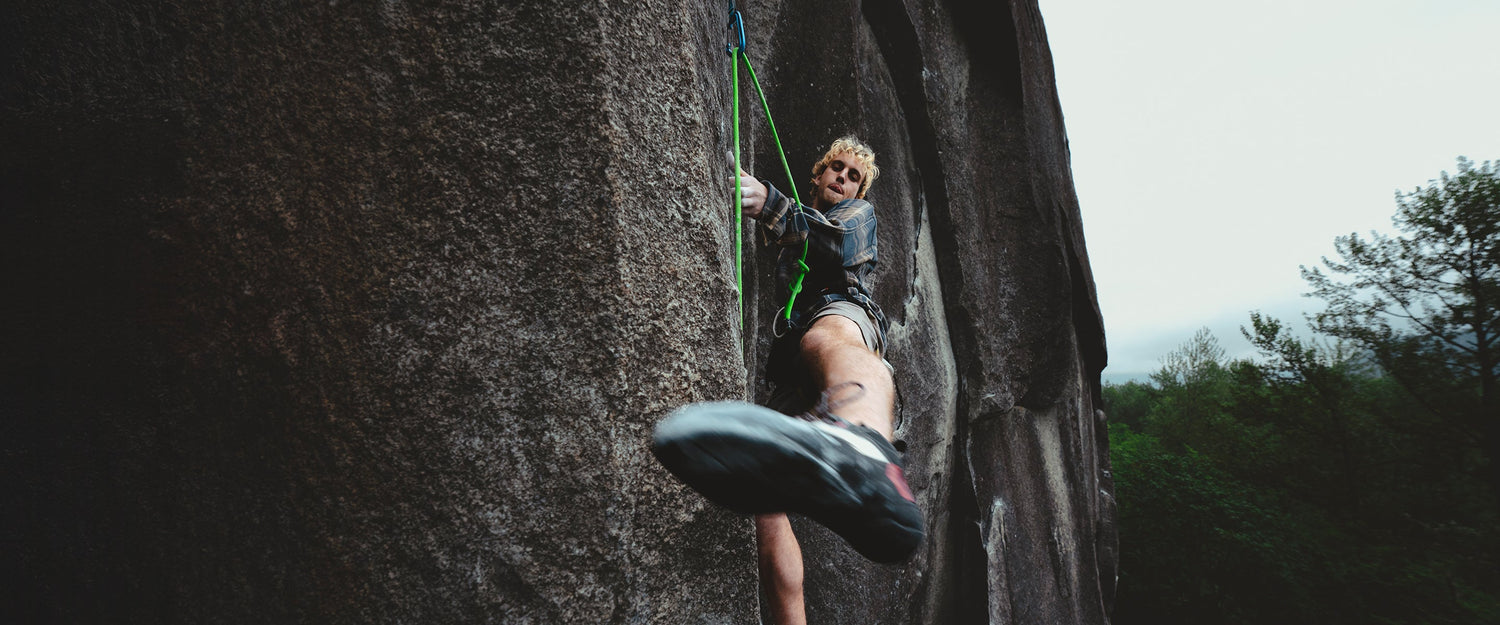 A climber swings his leg to toehook a cliff