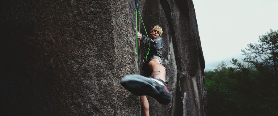 A climber swings his leg to toehook a cliff
