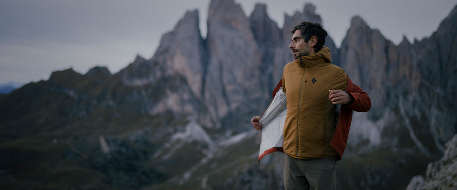 A man putting on a jacket in the Dolomites