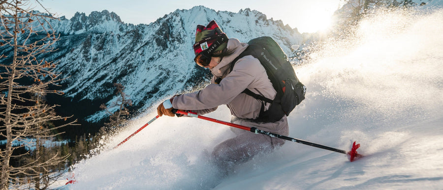 A skier carrying her skis against a blue sky background