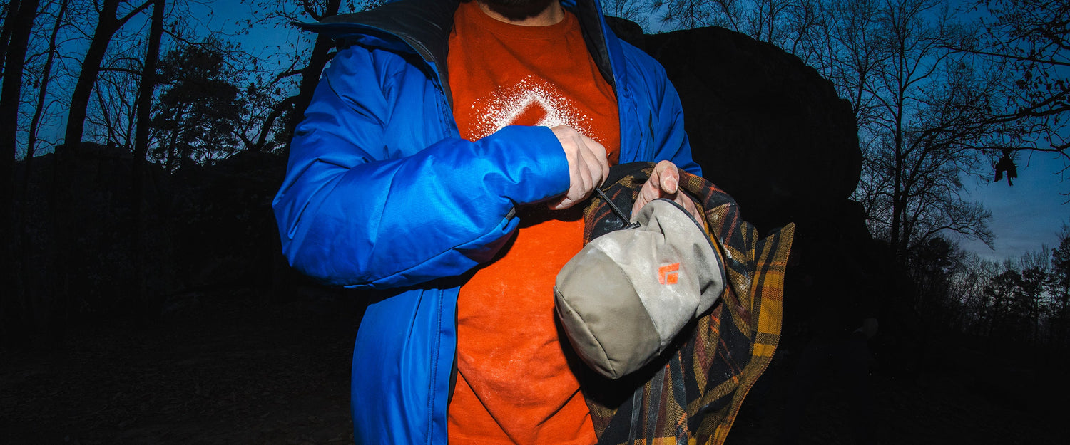 In the dark, a climber cinches their chalk bag. 