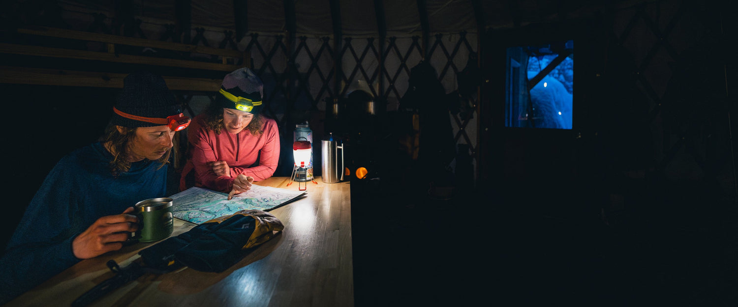 BD athletes Dorian and Maya look over a map by lantern light