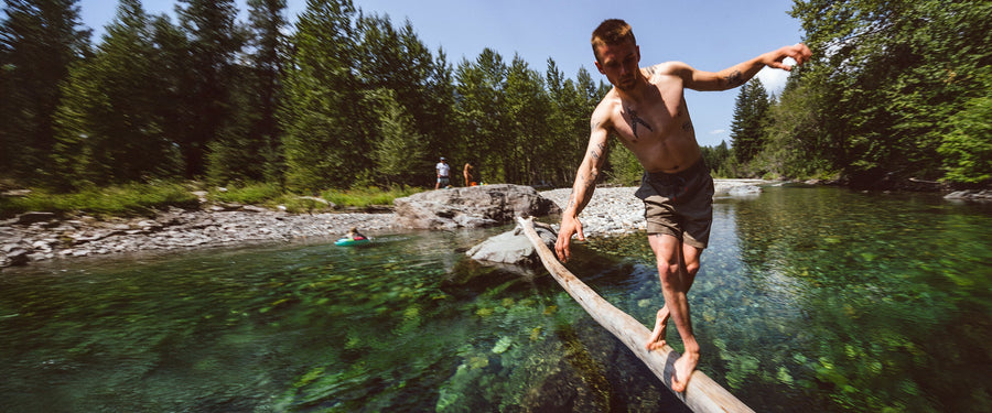 A climber balances on a log over water