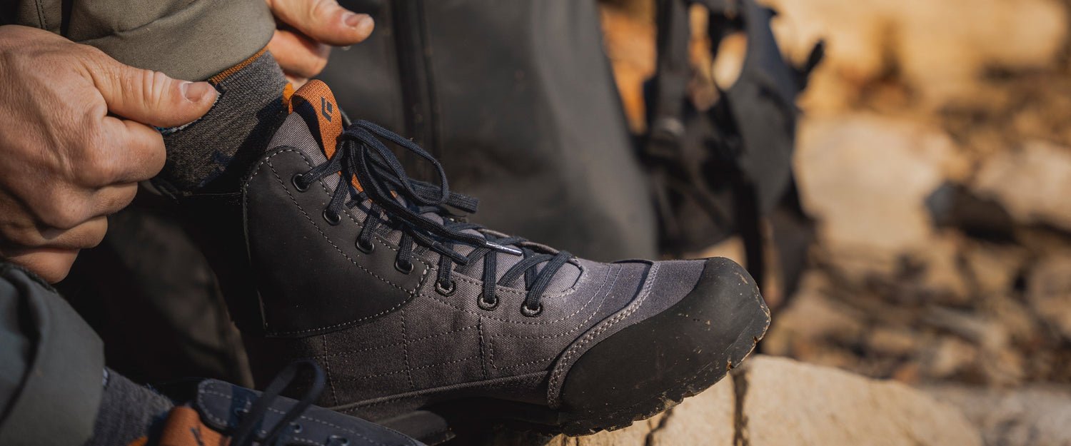 A person adjusts their circuit mid shoe on a rock