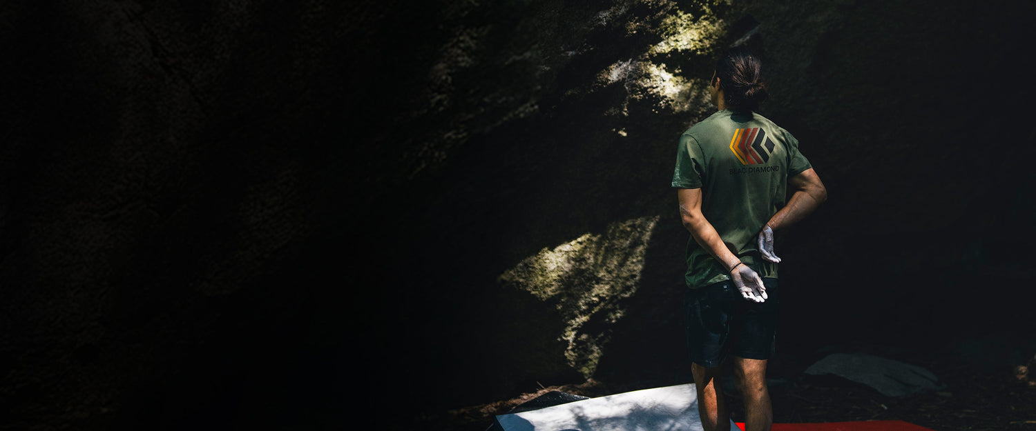 A climber surveys a boulder with his hands behind his back