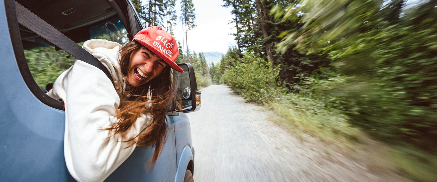 A climber wearing a Black Diamond hat hangs out of a van window
