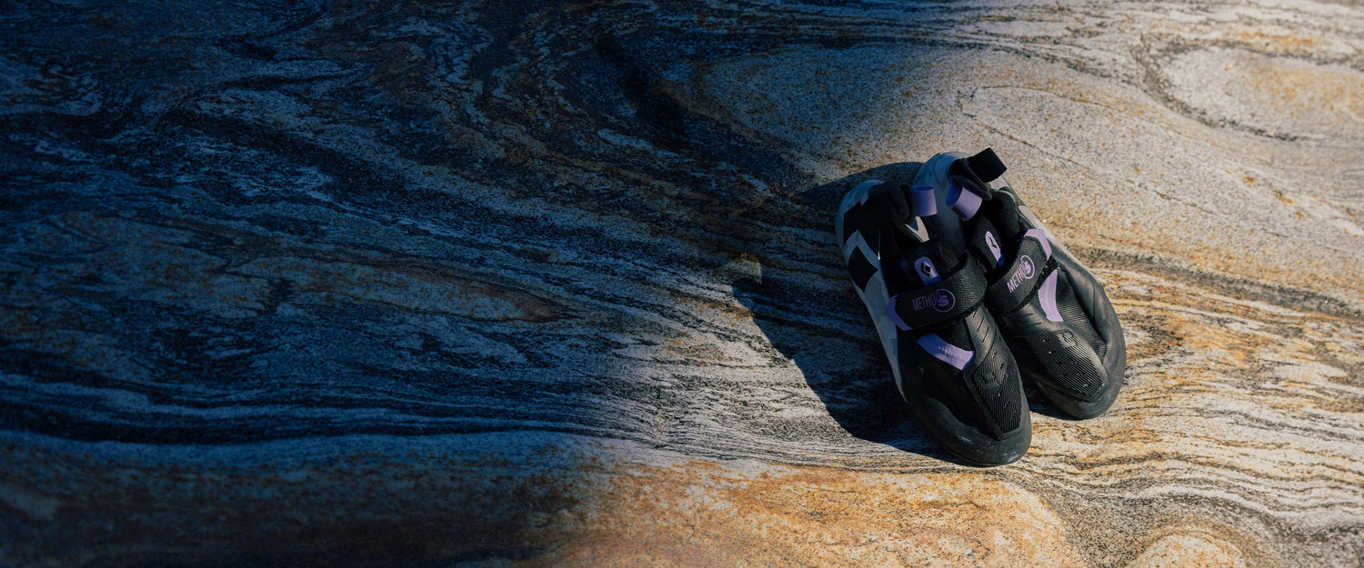 A pair of Method S climbing shoes sitting on a rock