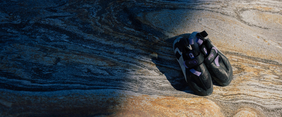 A pair of Method S climbing shoes sitting on a rock