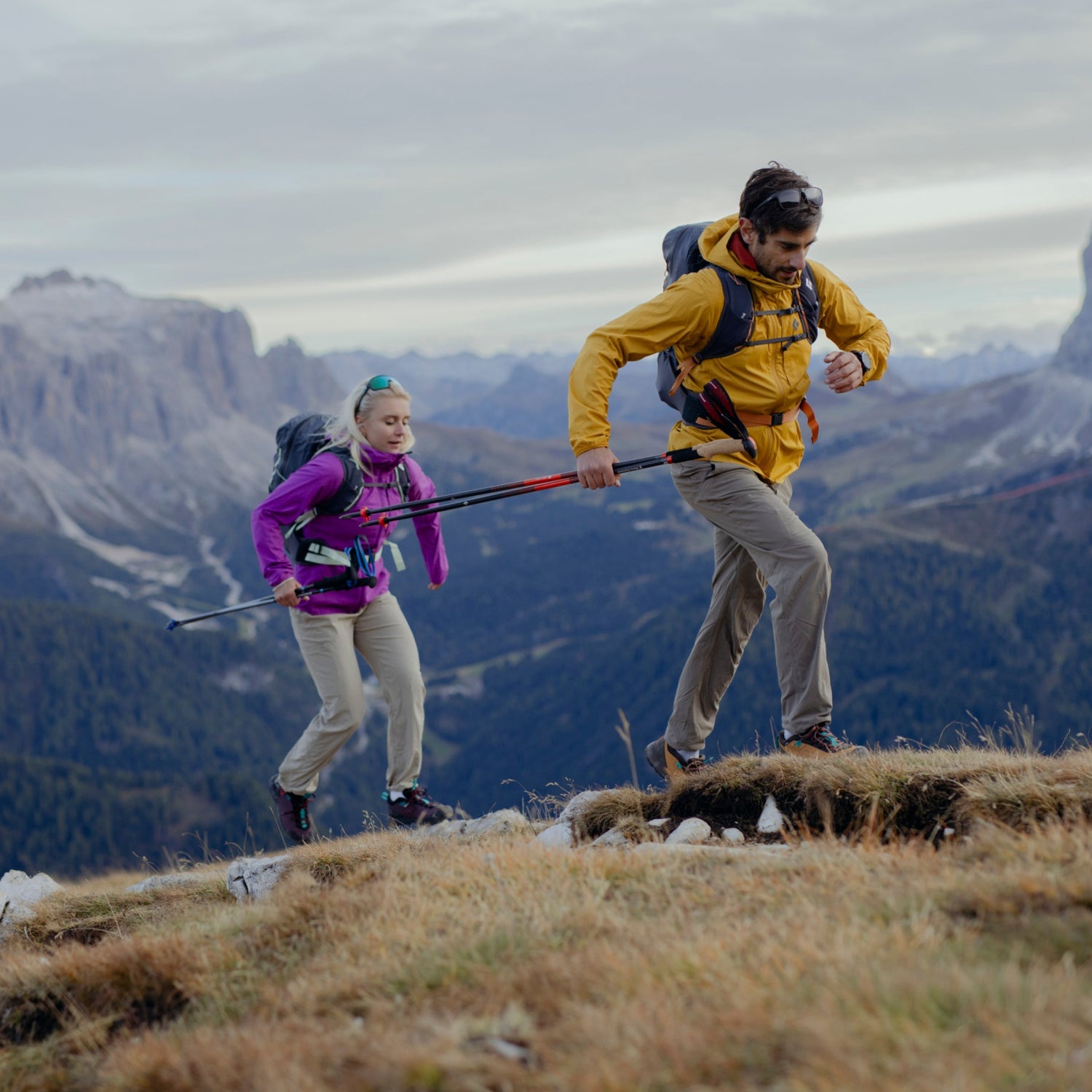 Two hikers in the BD Pursuit Collection jog up a hill. 