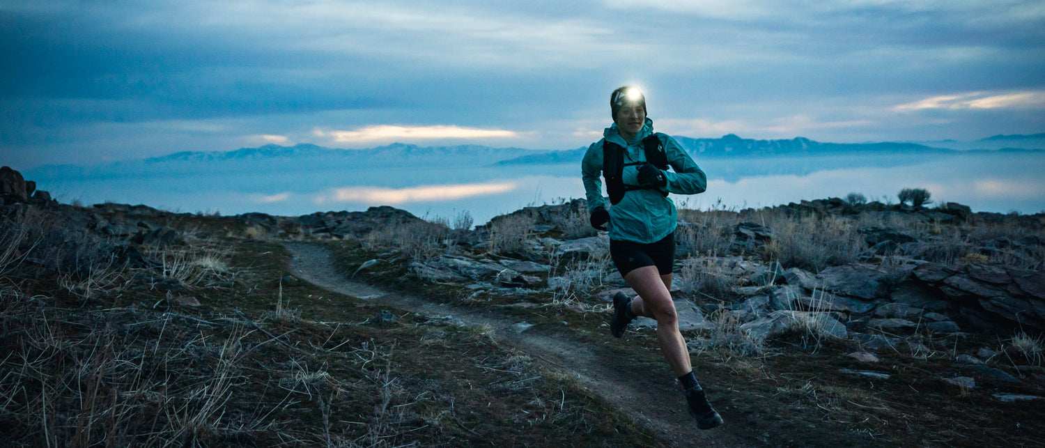 BD athlete Hillary Gerardi runs on a trail at dawn with a headlamp. 