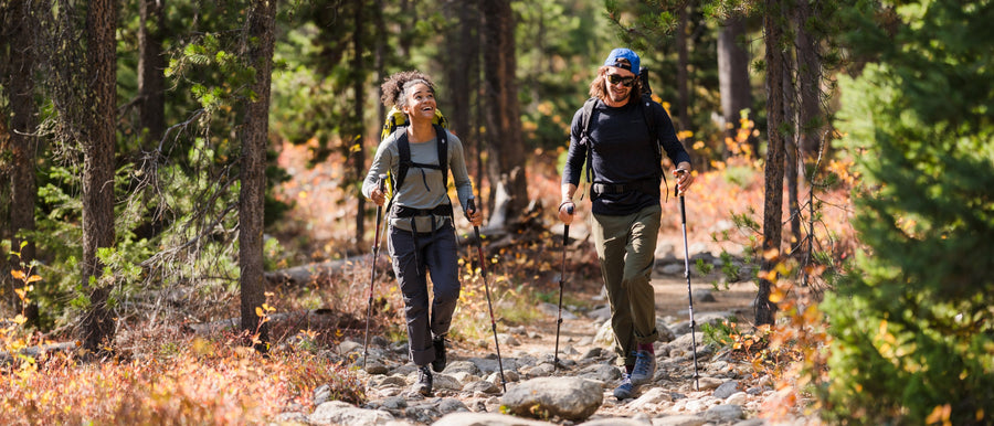 Two hikers in the forest use Black Diamond trekking poles. 