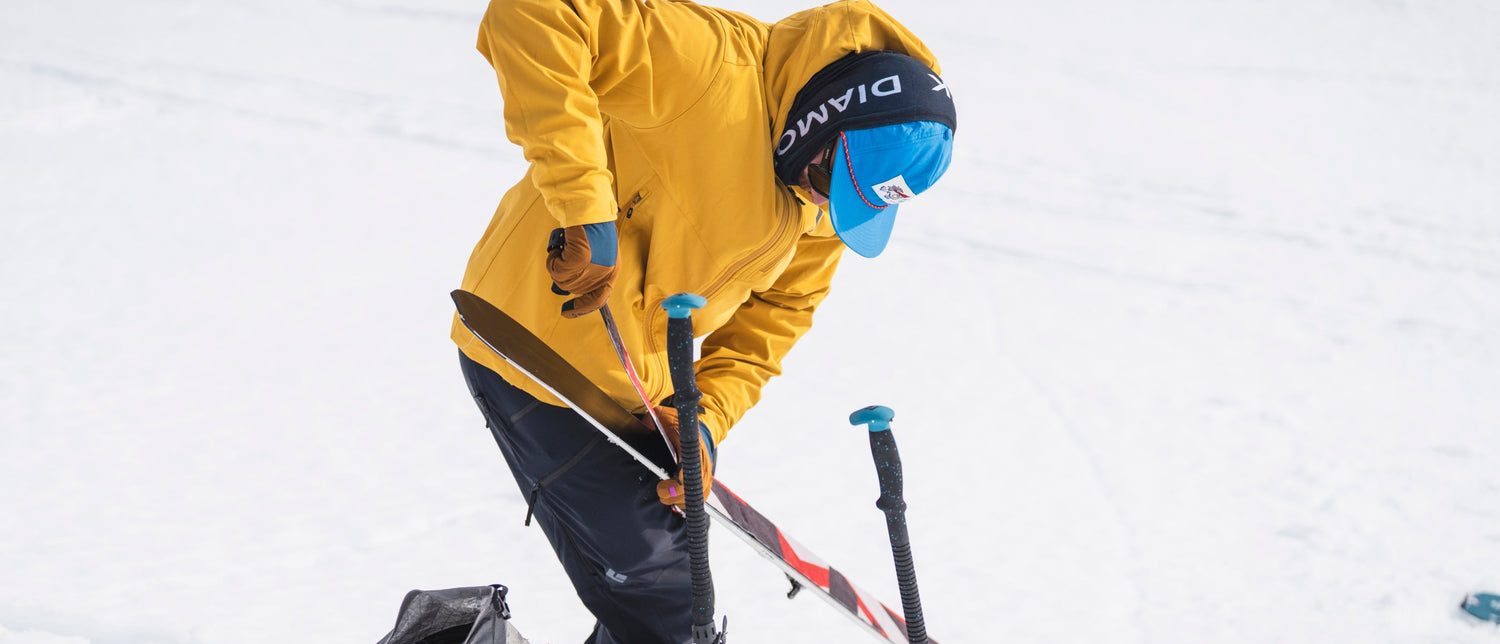A skier puts on climbing skins on his skis. 