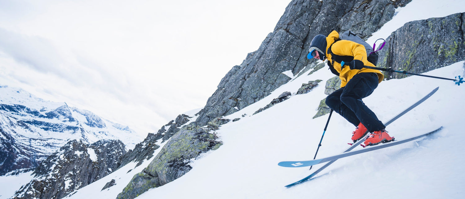 Skier in mid-air against a mountainous snowy landscape