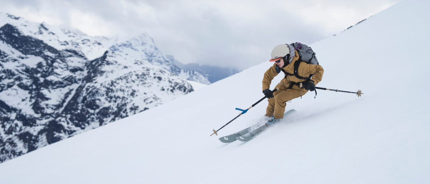 Person skiing down a snowy mountain with backpack and skis