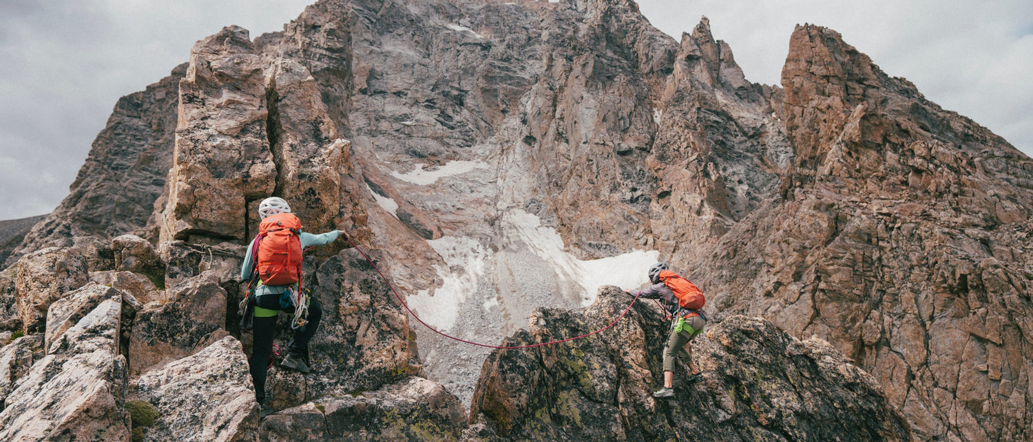 Two climbers in the Tetons with a cloudy sky.
