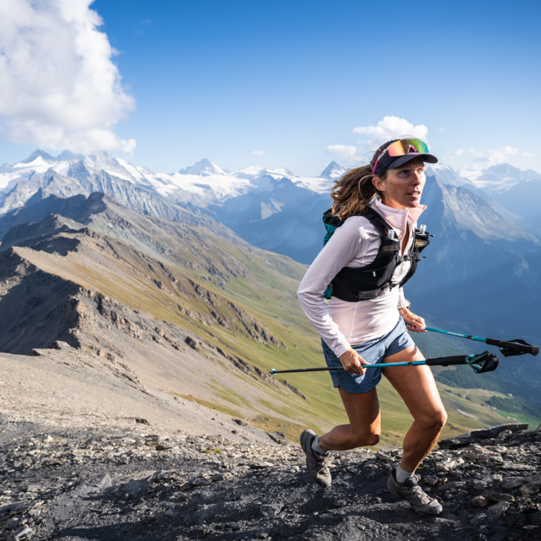 A runner on an epic ridgeline holds Distance Trekking Poles. 
