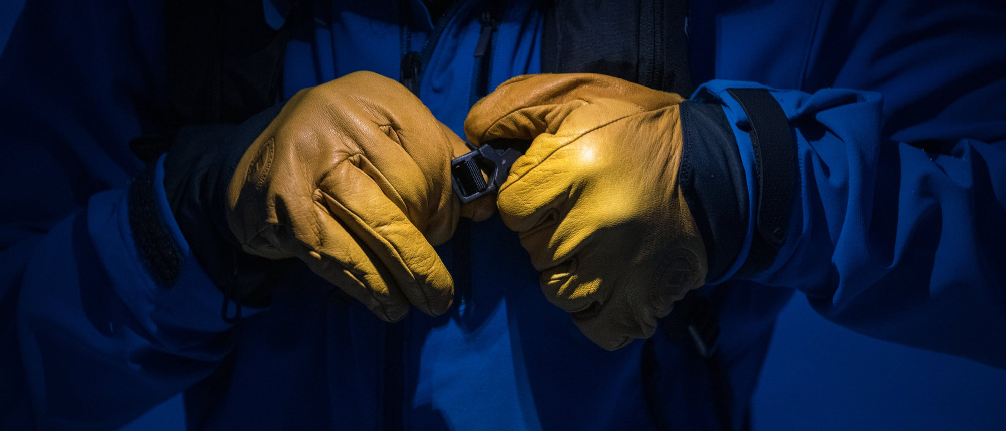 A skier wearing Black Diamond gloves clips the sternum strap on their pack. 
