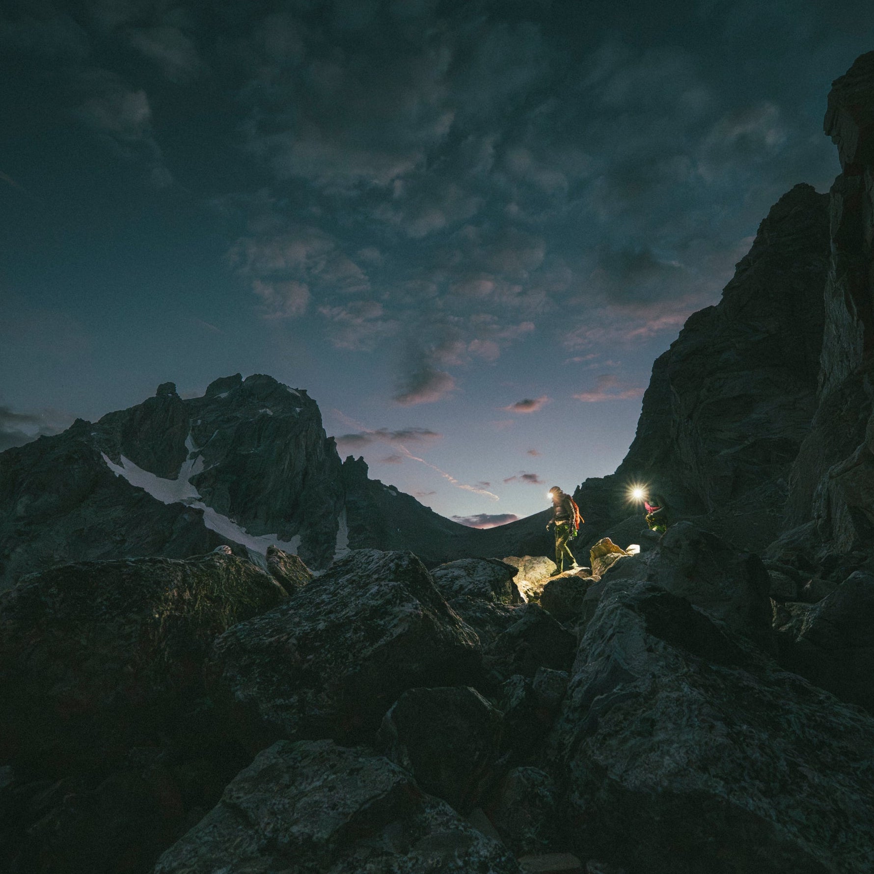 Two hikers in the alpine illuminate their path with Black Diamond headlamps. 